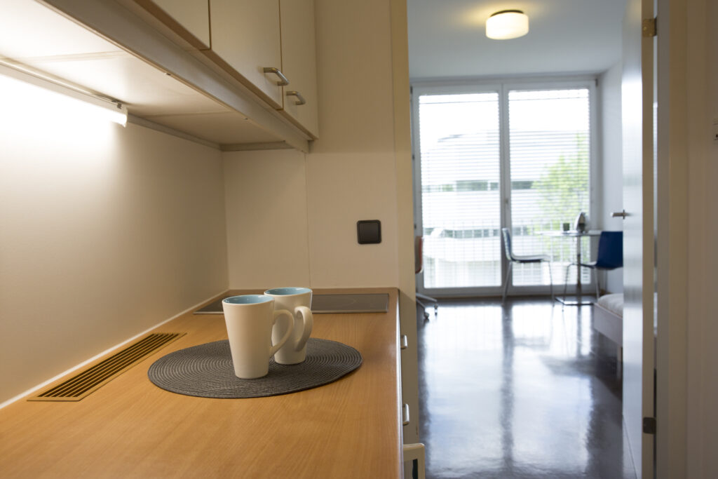 Blick in eine kleine Studentenwohnung im Vordergrund Küchenzeile im Hintergrund Raum mit großem Fenster